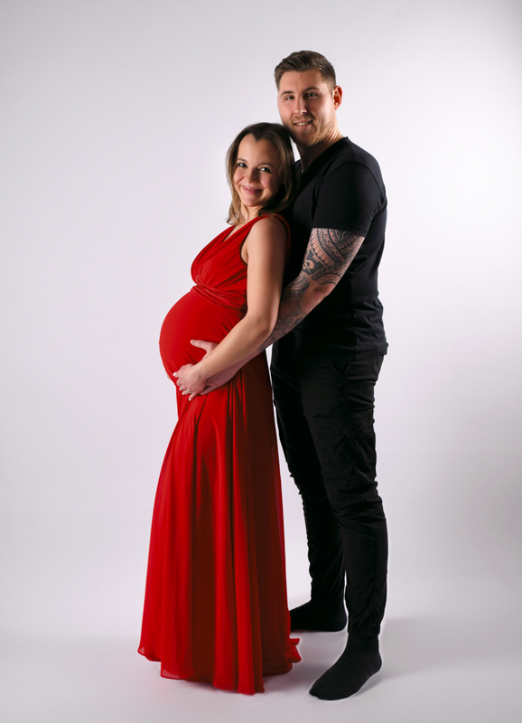 Schwangeres Pärchen im roten Kleid Ganzkörper