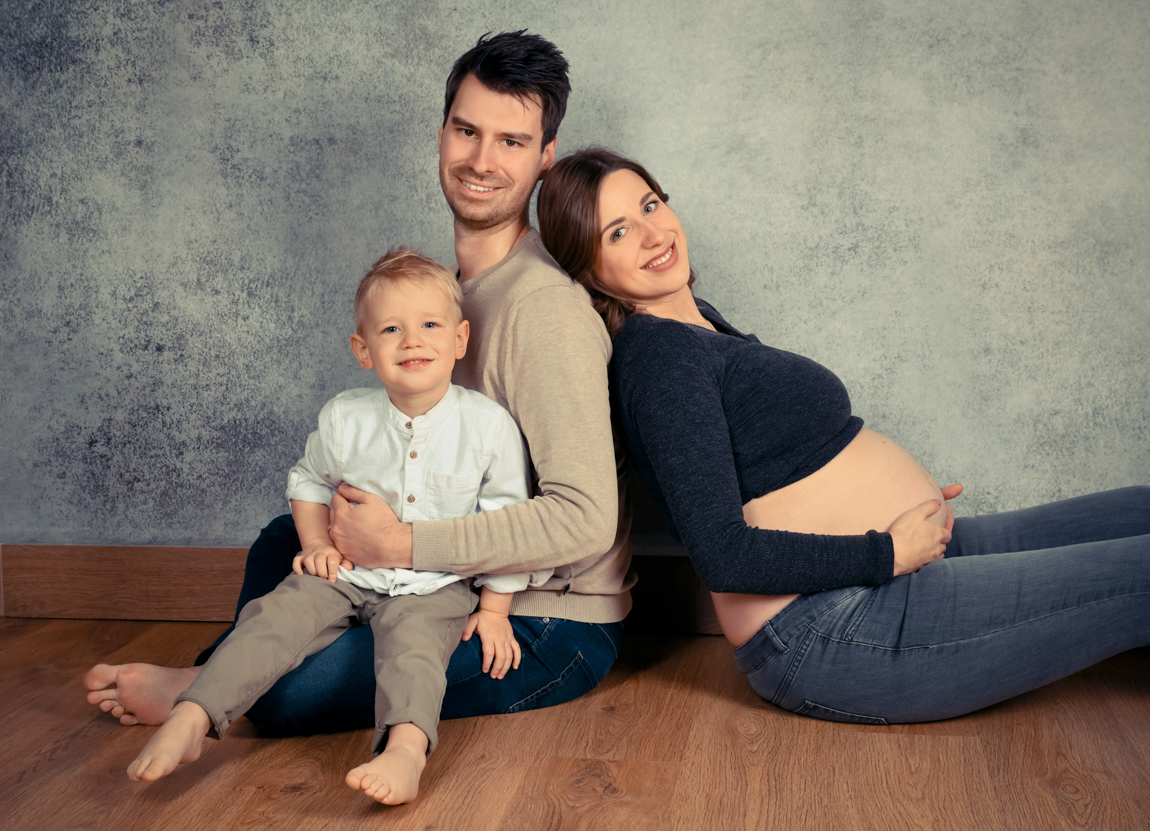 Familie mit schwangerer Mama sitzend