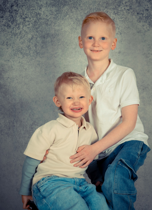 Geschwister lachend vor grauer wand